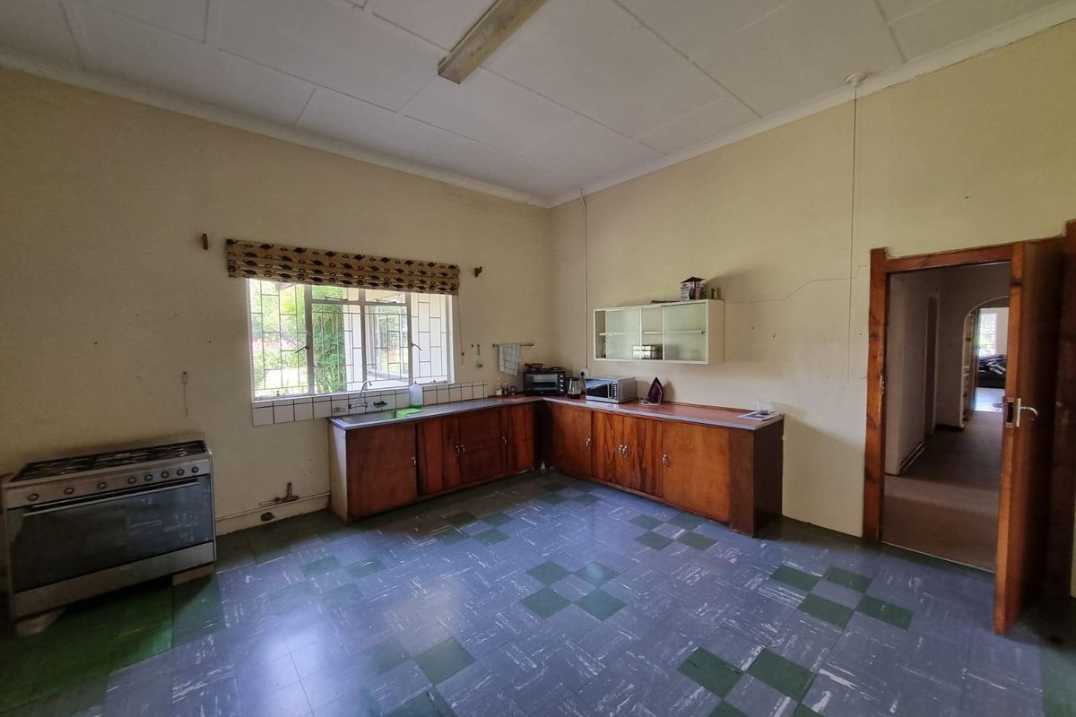 A dated kitchen featuring original wooden cabinetry, a freestanding gas stove, and vinyl flooring, offering significant potential for a modern renovation.