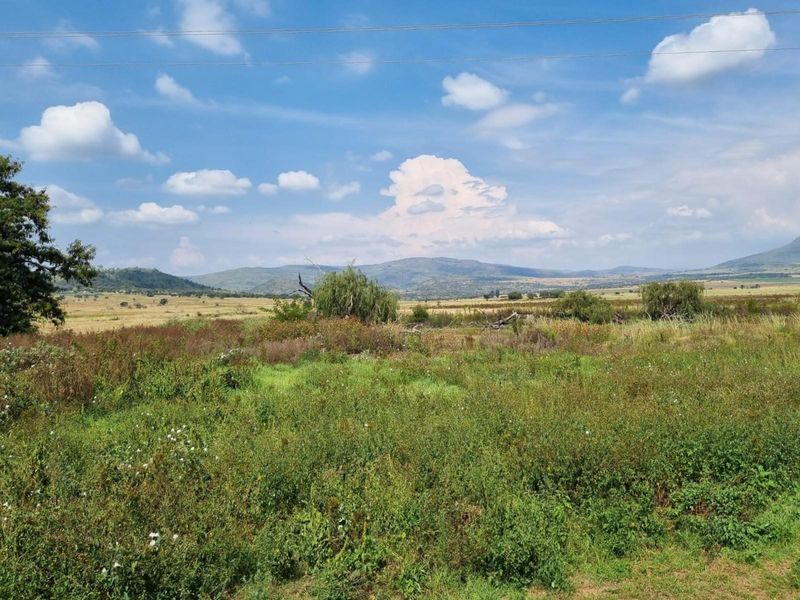 A scenic landscape view showcasing the expansive open fields and rolling hills characteristic of the surrounding farm property.