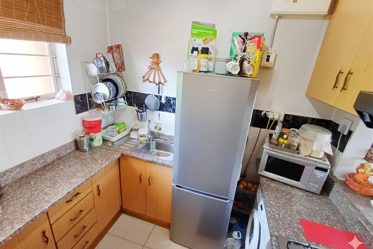 Compact kitchen featuring laminate cabinetry, durable countertops, tiled backsplash, and integrated hob, providing a functional workspace within the apartment.