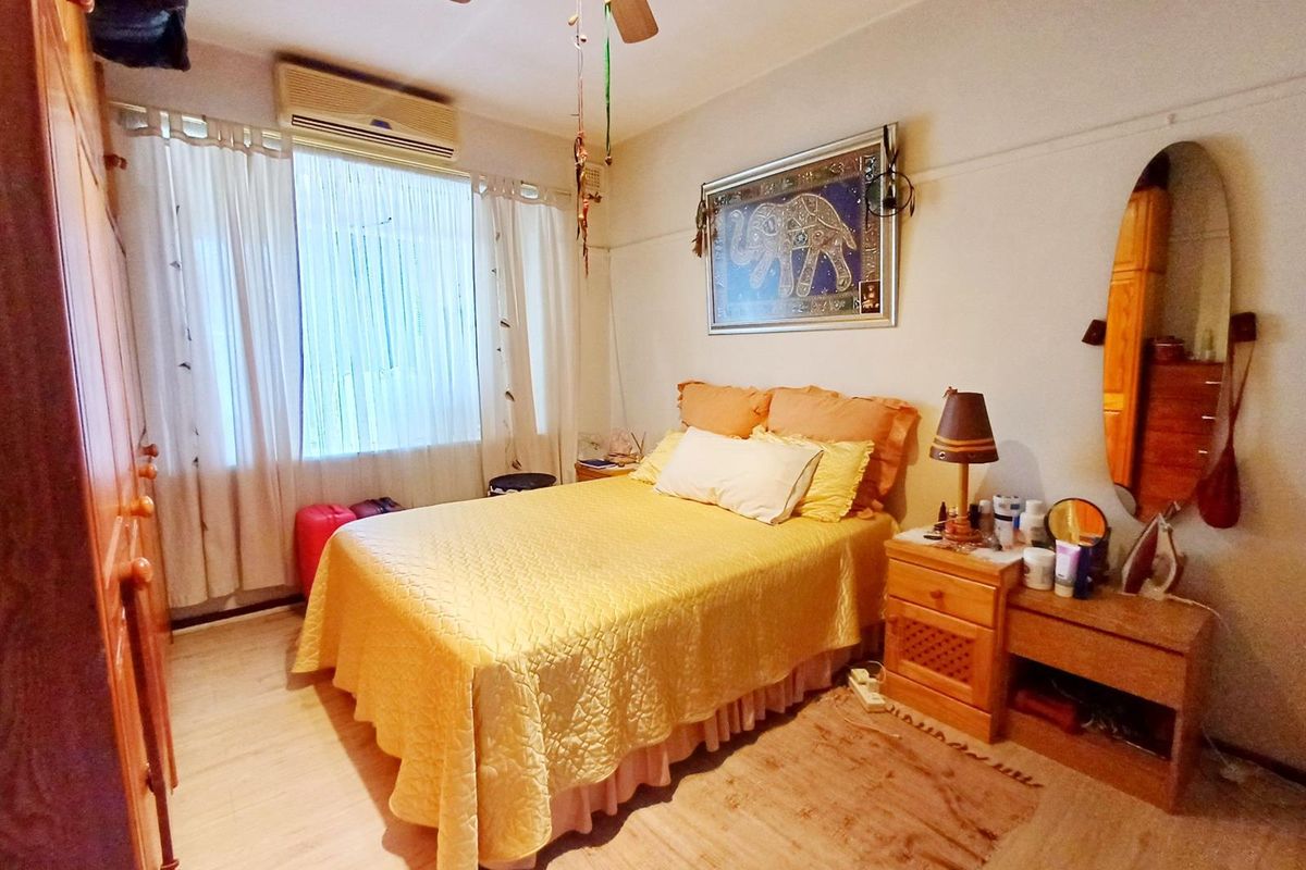 A functional bedroom featuring a ceiling fan, wall-mounted air conditioning unit, and built-in wardrobe storage.