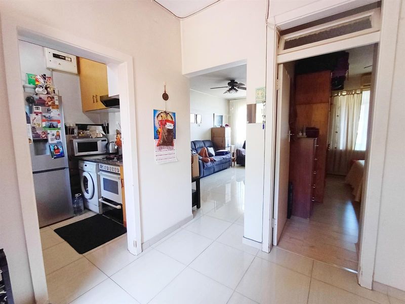 A central hallway providing access to the kitchen, living area, and bedroom, featuring neutral tiled flooring throughout the apartment.