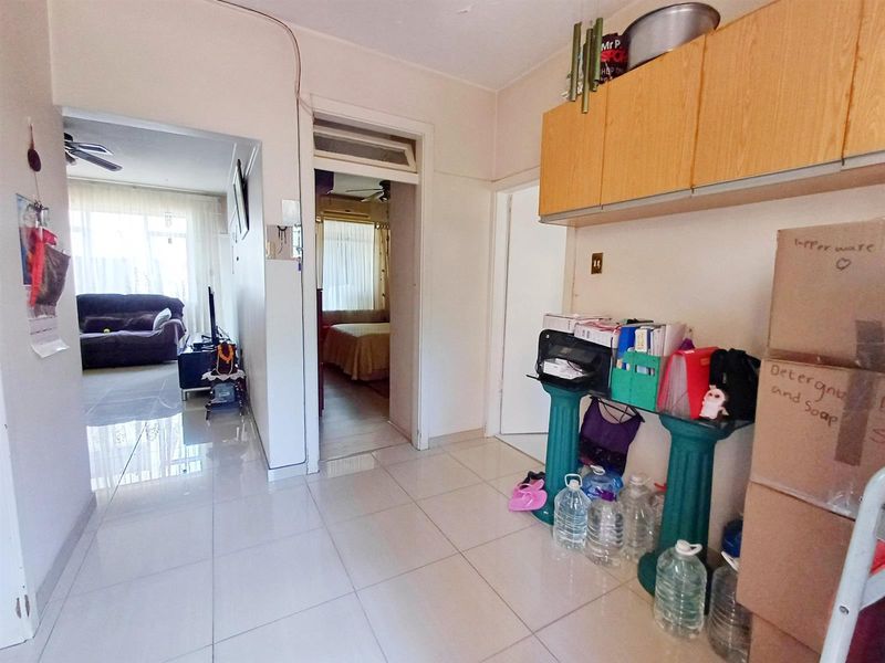 A functional hallway featuring tiled flooring and built-in overhead storage cabinetry, providing access to adjacent living and bedroom areas.