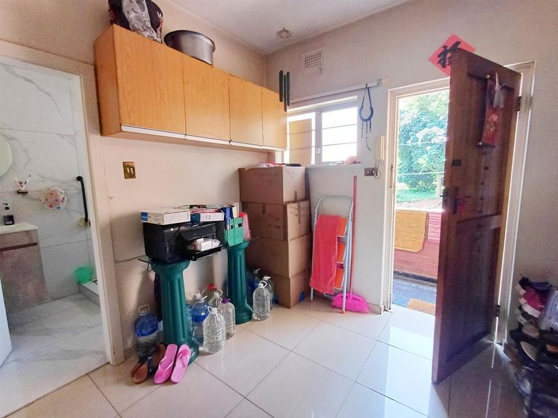 Entrance area featuring tiled flooring, built-in overhead storage cabinetry, and direct access to the exterior through a timber door.