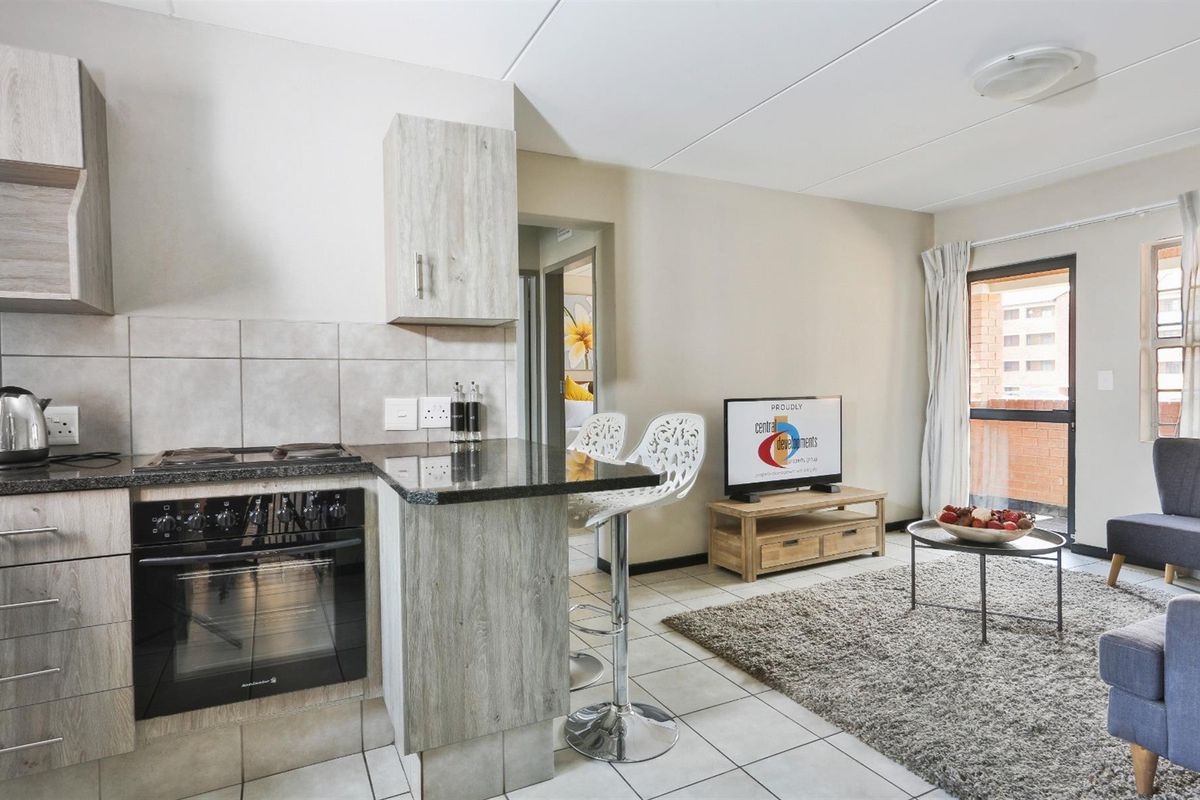 Open-plan living area featuring a modern kitchen with granite countertops, built-in oven and hob, and direct access to a private balcony.
