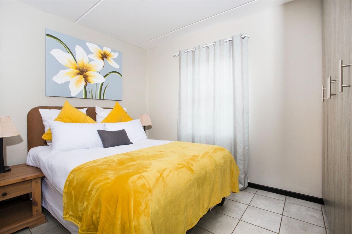 A well-maintained bedroom featuring neutral walls, tiled flooring, and a built-in wardrobe, offering a clean and functional living space.