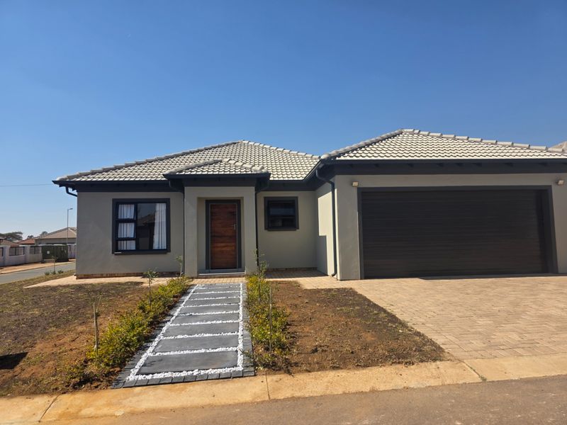 Modern single-story residential home featuring a tiled roof, double garage, paved driveway, and a landscaped stone walkway leading to the front entrance.