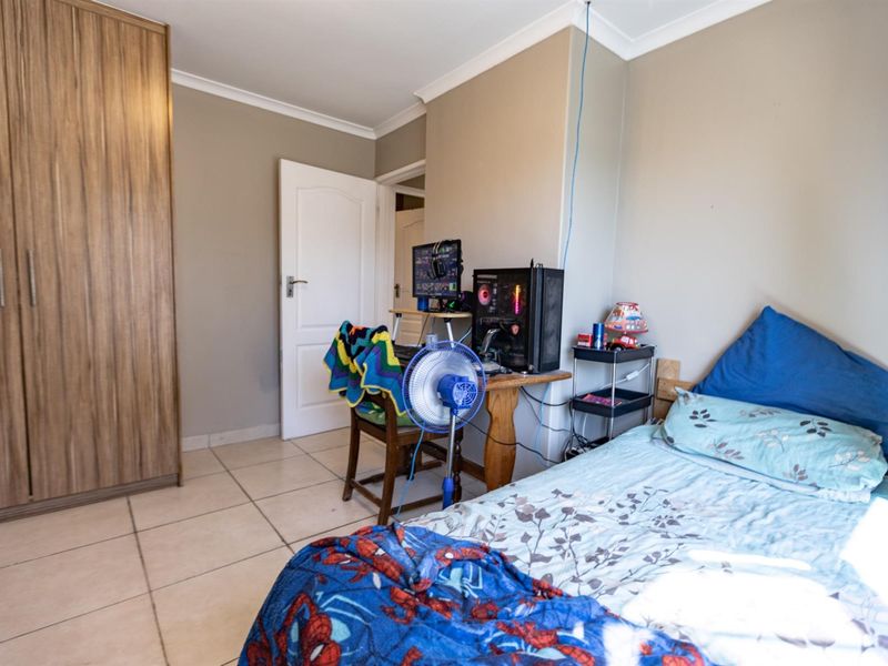 A functional bedroom featuring tiled flooring, a built-in wardrobe, and coved ceiling detailing.
