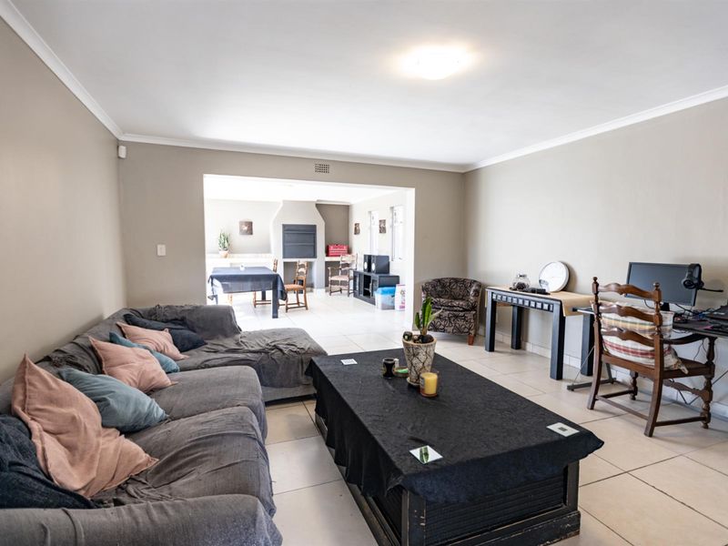 Spacious open-plan living area featuring tiled flooring, coved cornicing, and a built-in fireplace in the adjacent dining or entertainment space.