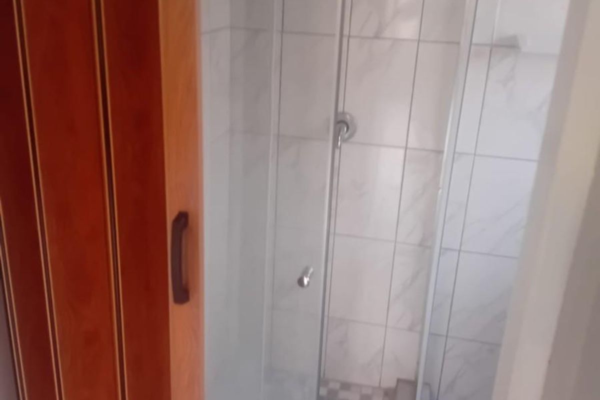 A compact bathroom featuring a glass-enclosed shower stall with tiled walls and a mosaic-style shower floor.