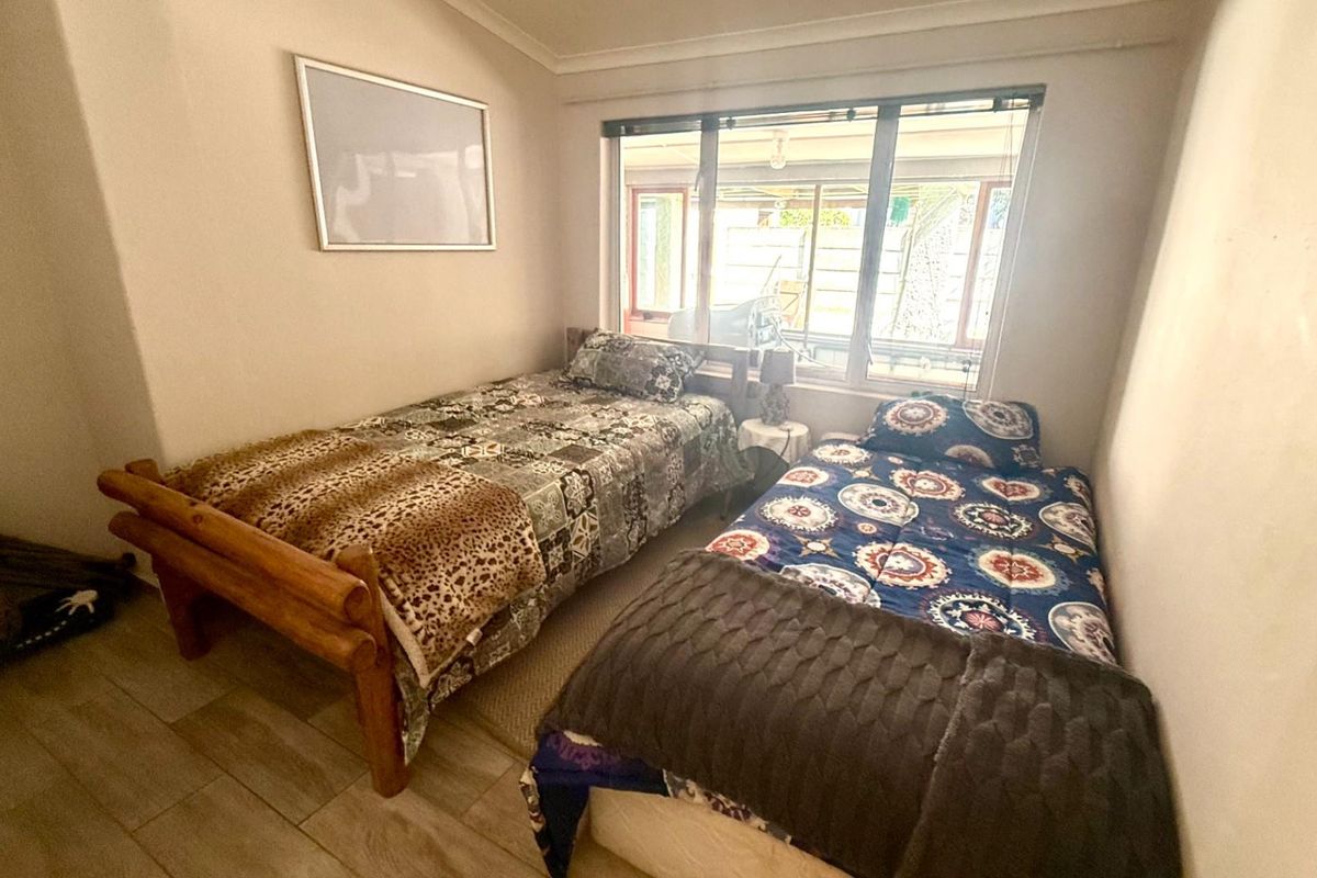 A functional bedroom featuring tiled flooring, large windows providing natural light, and neutral wall finishes.