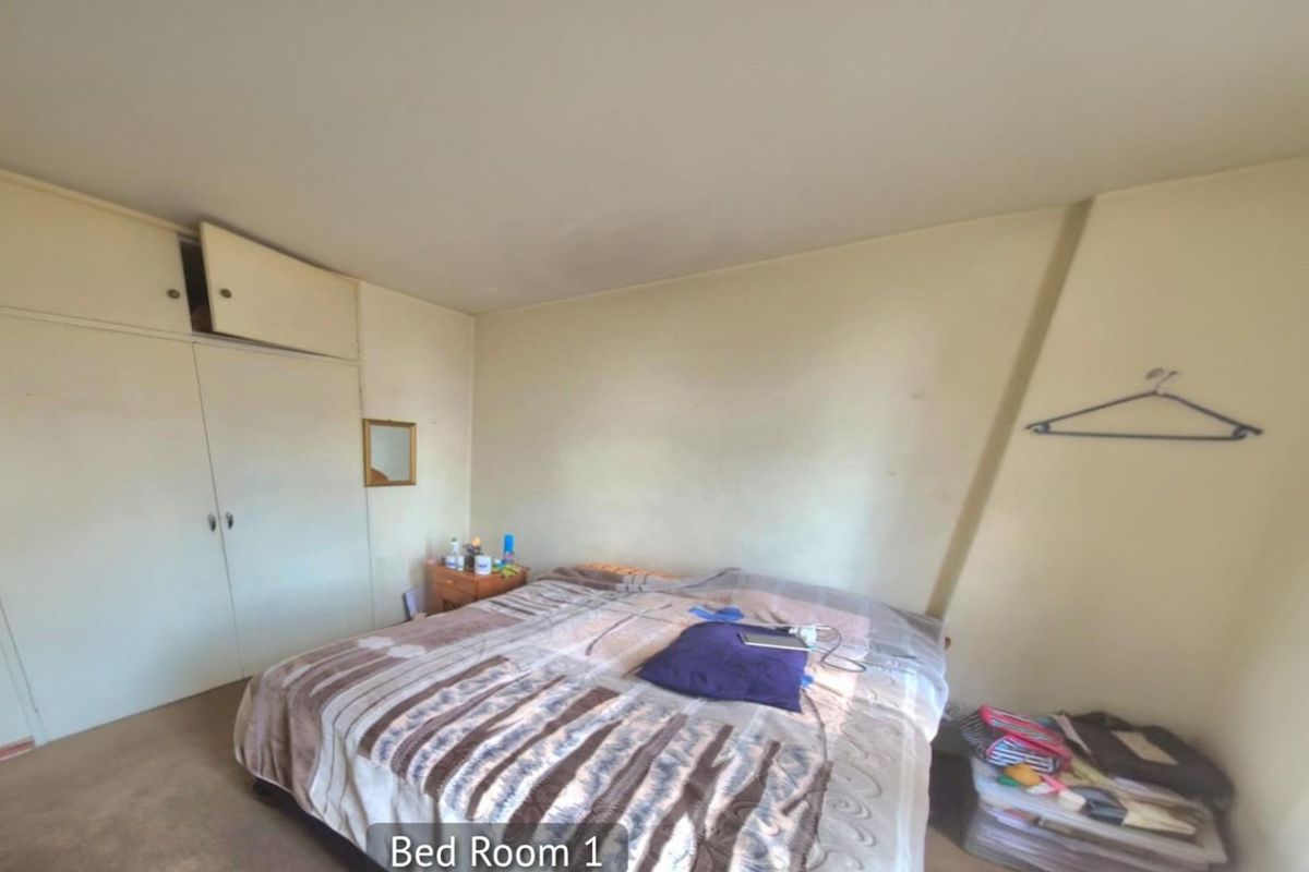 A bedroom featuring built-in cupboards with overhead storage and carpeted flooring.