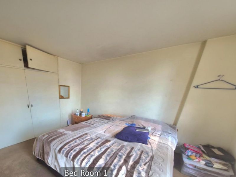A bedroom featuring built-in cupboards with overhead storage and carpeted flooring.