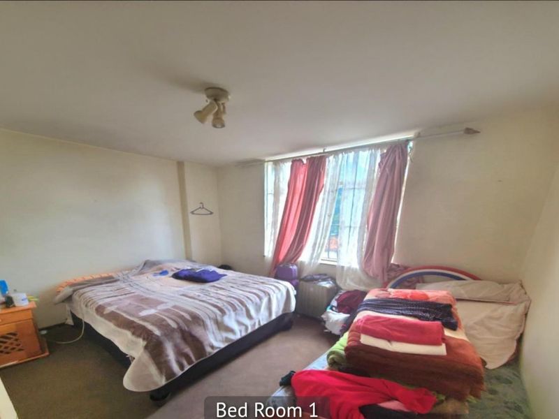 A bedroom featuring carpeted flooring and a large window with natural light, providing a functional space for rest.