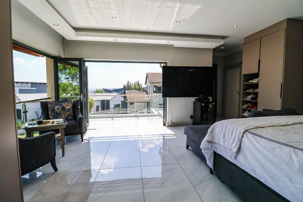Spacious bedroom featuring large format floor tiles, recessed ceiling lighting, built-in cabinetry, and expansive folding doors opening onto a private balcony.