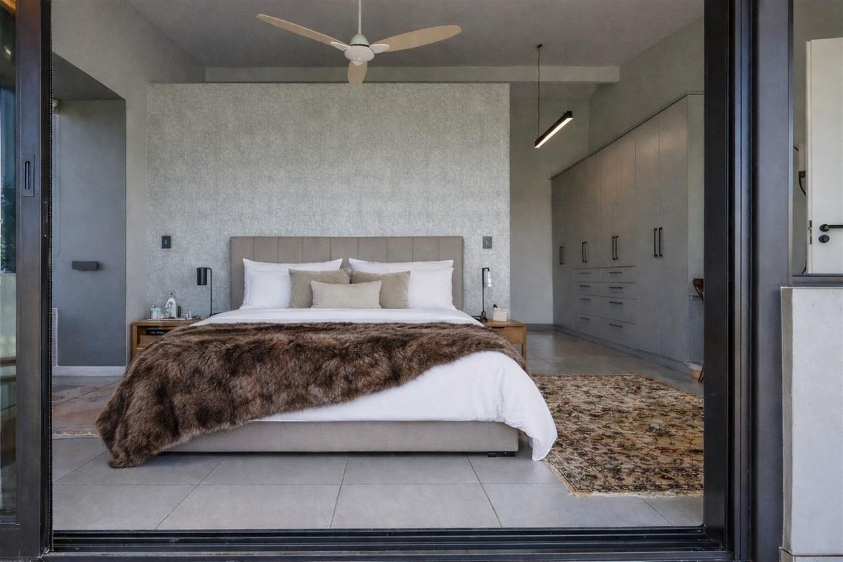 Spacious modern bedroom featuring built-in floor-to-ceiling cabinetry, tiled flooring, and a ceiling fan, offering a clean and contemporary aesthetic.