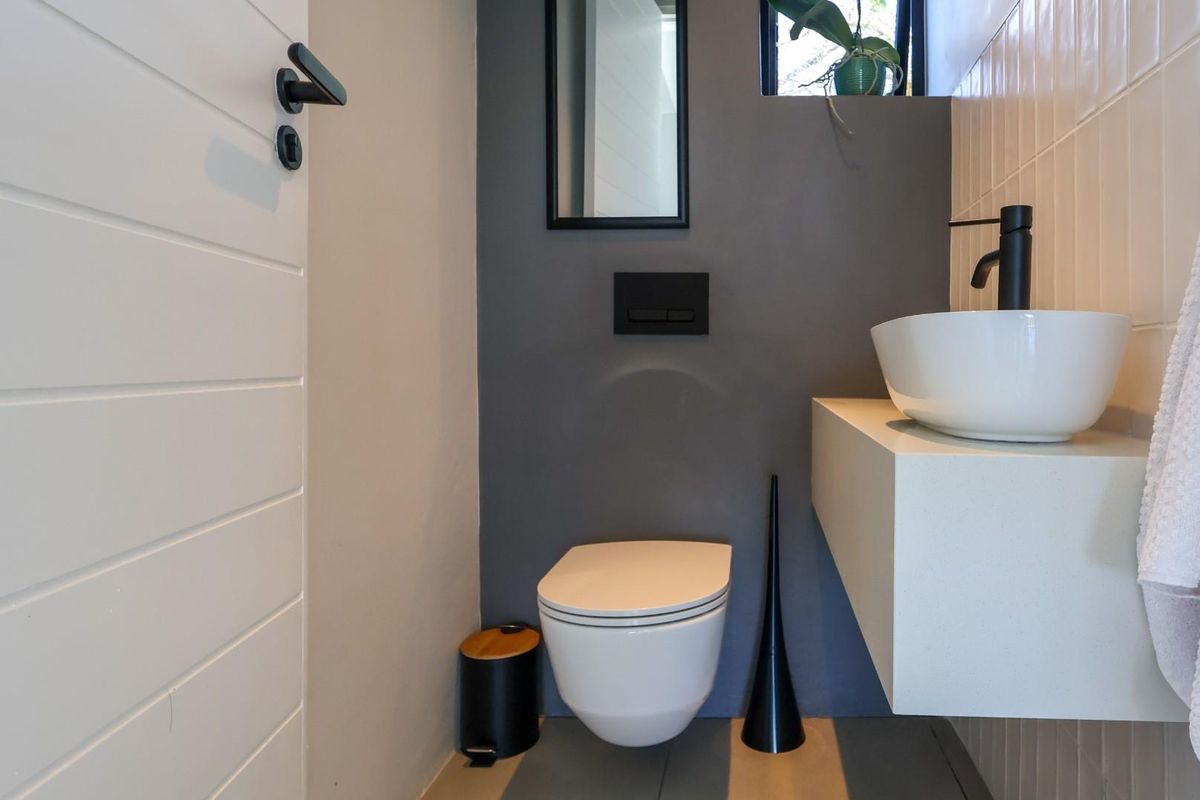 Modern guest bathroom featuring a wall-mounted toilet, floating vanity with a vessel sink, and contemporary matte black fixtures.