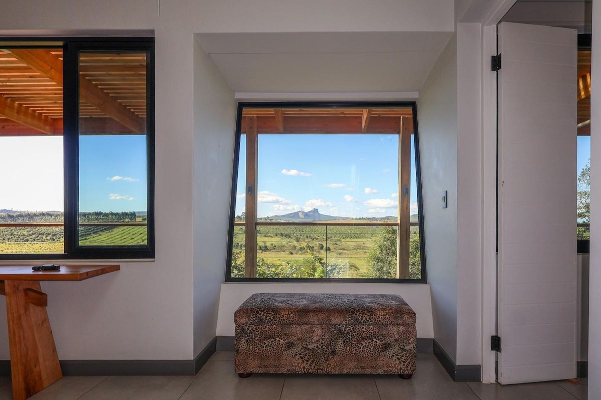 A bright room featuring large picture windows with expansive rural landscape views, integrated timber shelving, and modern tiled flooring.