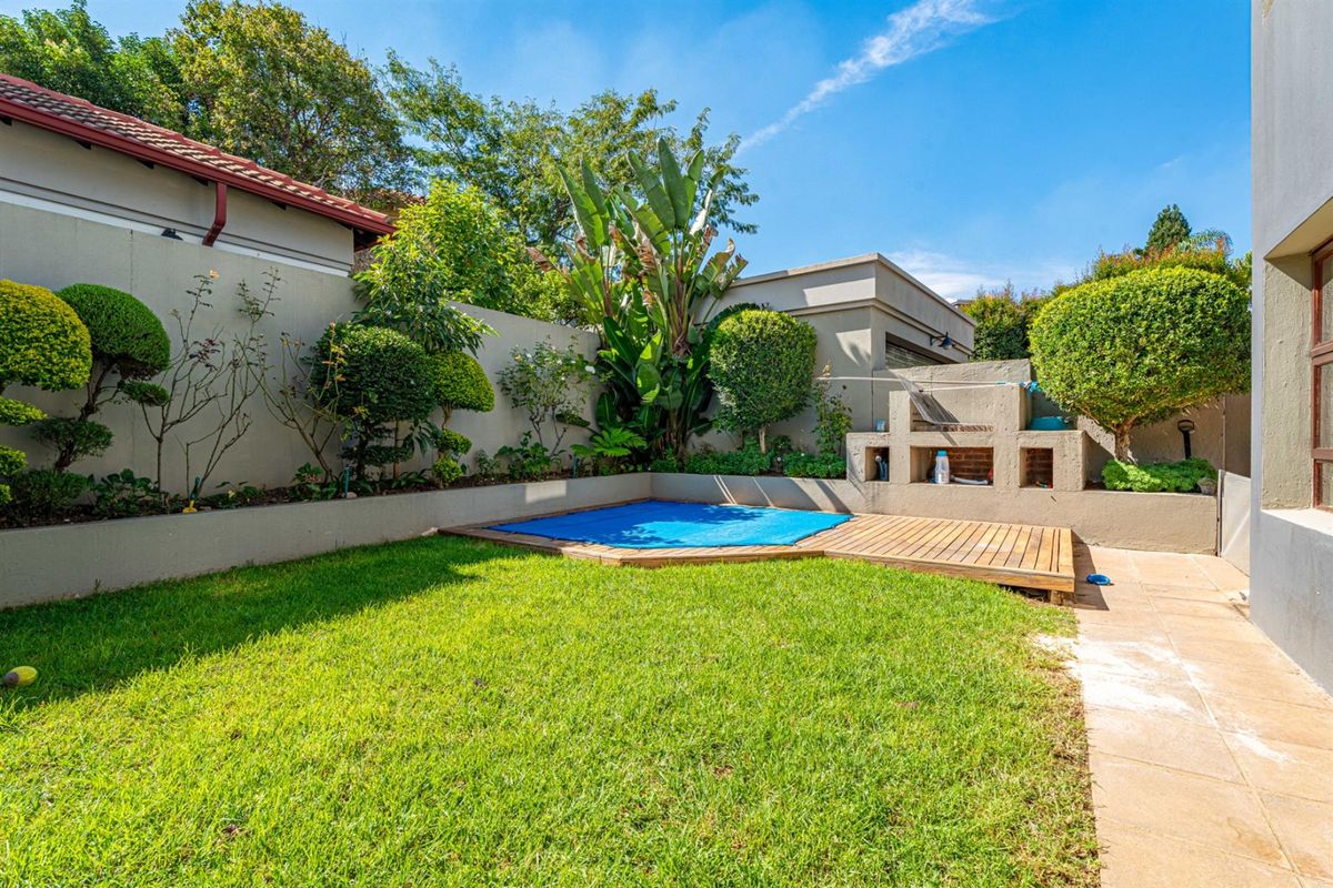 A well-maintained rear garden featuring a small plunge pool with a wooden deck surround and a built-in masonry braai area.