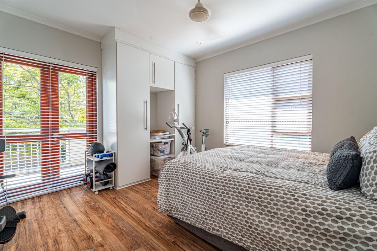 A bright bedroom featuring built-in cabinetry, wood-look flooring, and a glass door providing access to an outdoor balcony area.