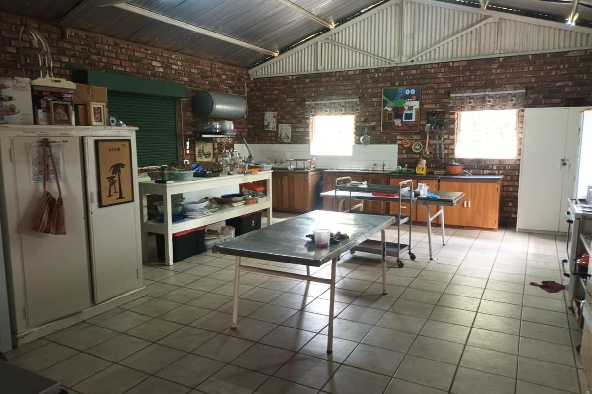A rustic, industrial-style kitchen featuring exposed brick walls, a high corrugated metal ceiling, tiled flooring, and functional built-in cabinetry.