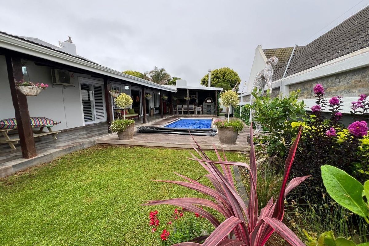 Rear garden area featuring a swimming pool with cover, wooden decking, and a covered patio area attached to the main house structure.