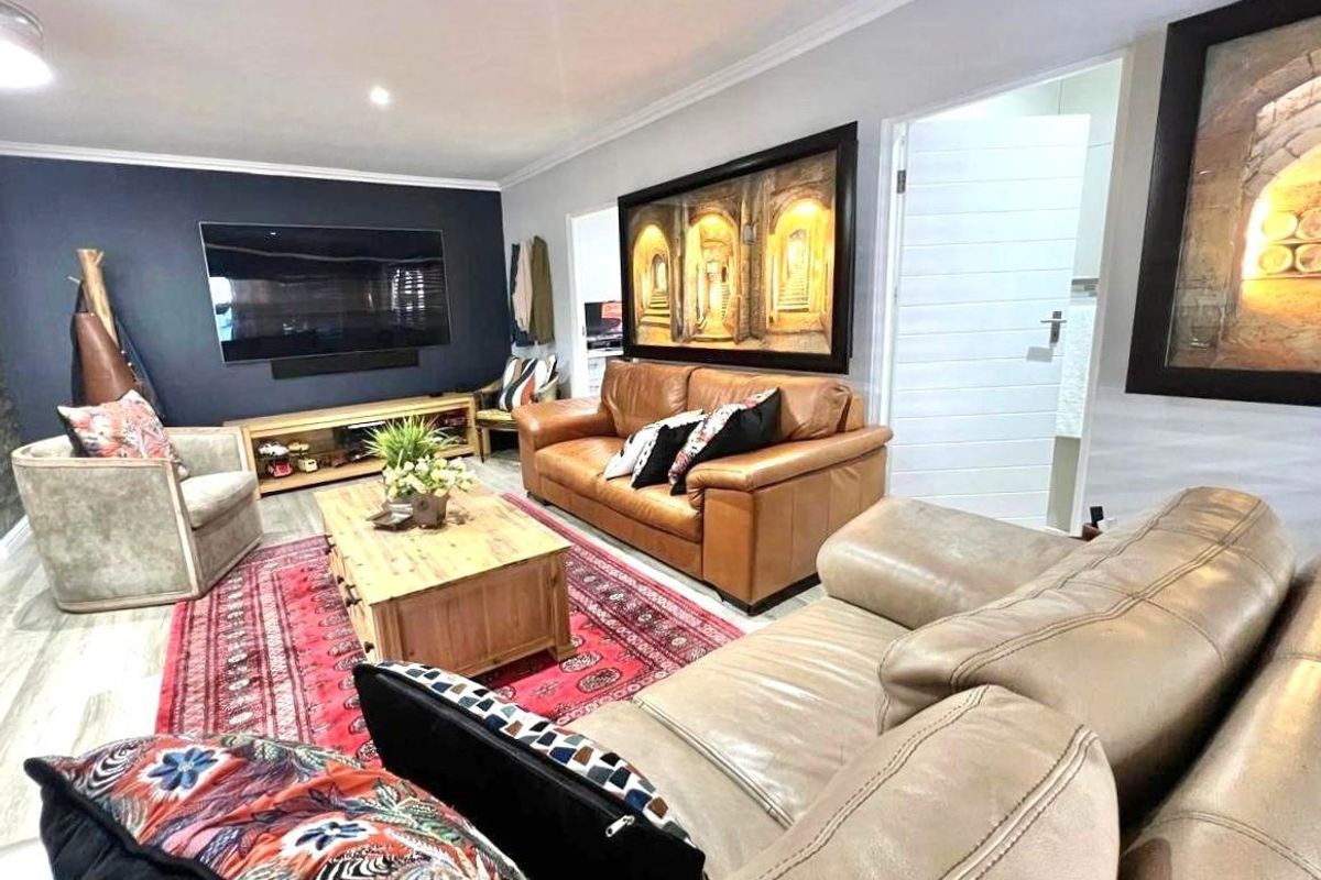 A comfortable living room featuring a dark accent wall, recessed lighting, and a modern door leading to an adjacent space.