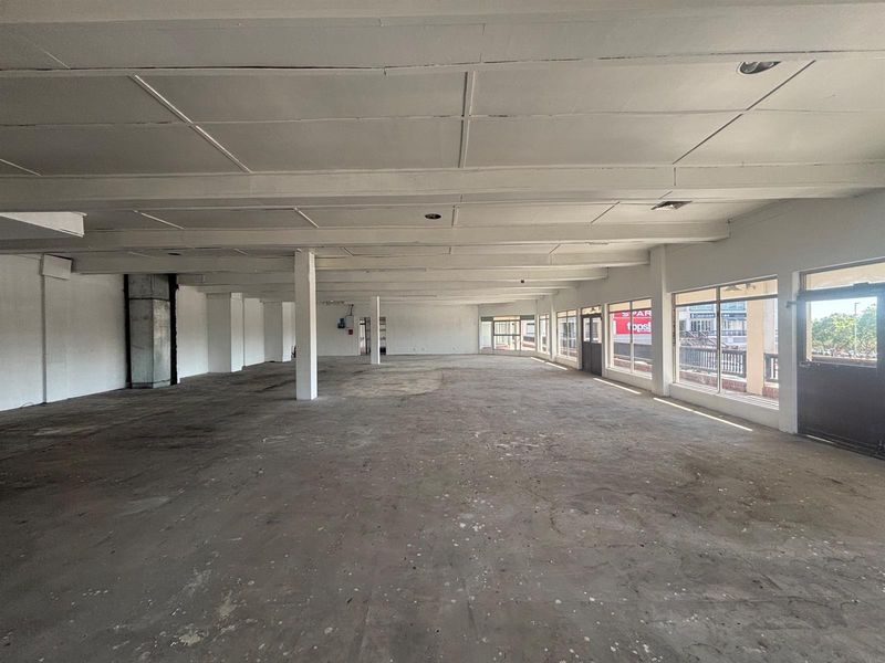 Spacious open-plan retail unit featuring large storefront windows, concrete flooring, and exposed structural columns, offering a versatile blank canvas for commercial use.