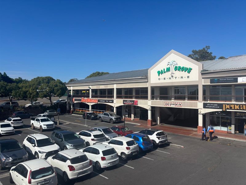 Exterior view of the Palm Grove Centre retail complex featuring a multi-tenant facade, covered parking area, and paved access.