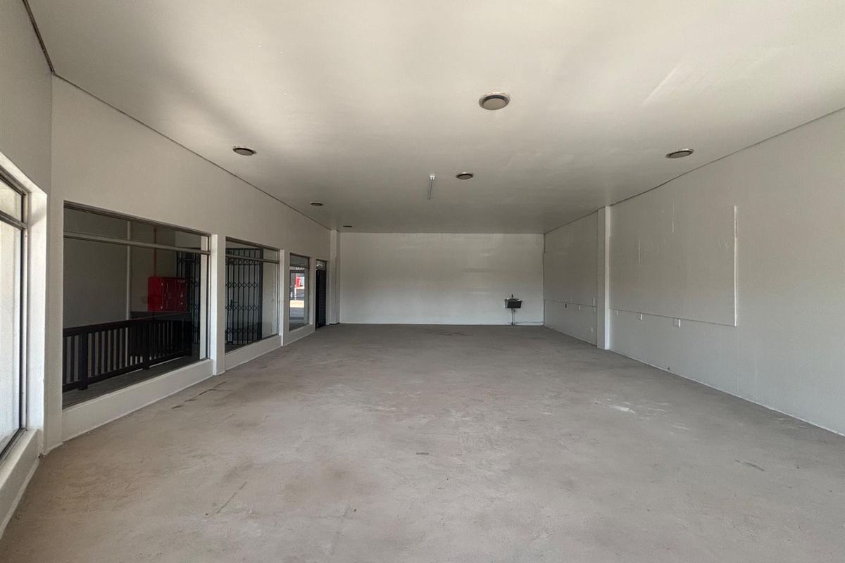 A spacious, empty retail unit featuring large display windows, recessed downlights, and concrete flooring, offering a blank canvas for various commercial business applications.