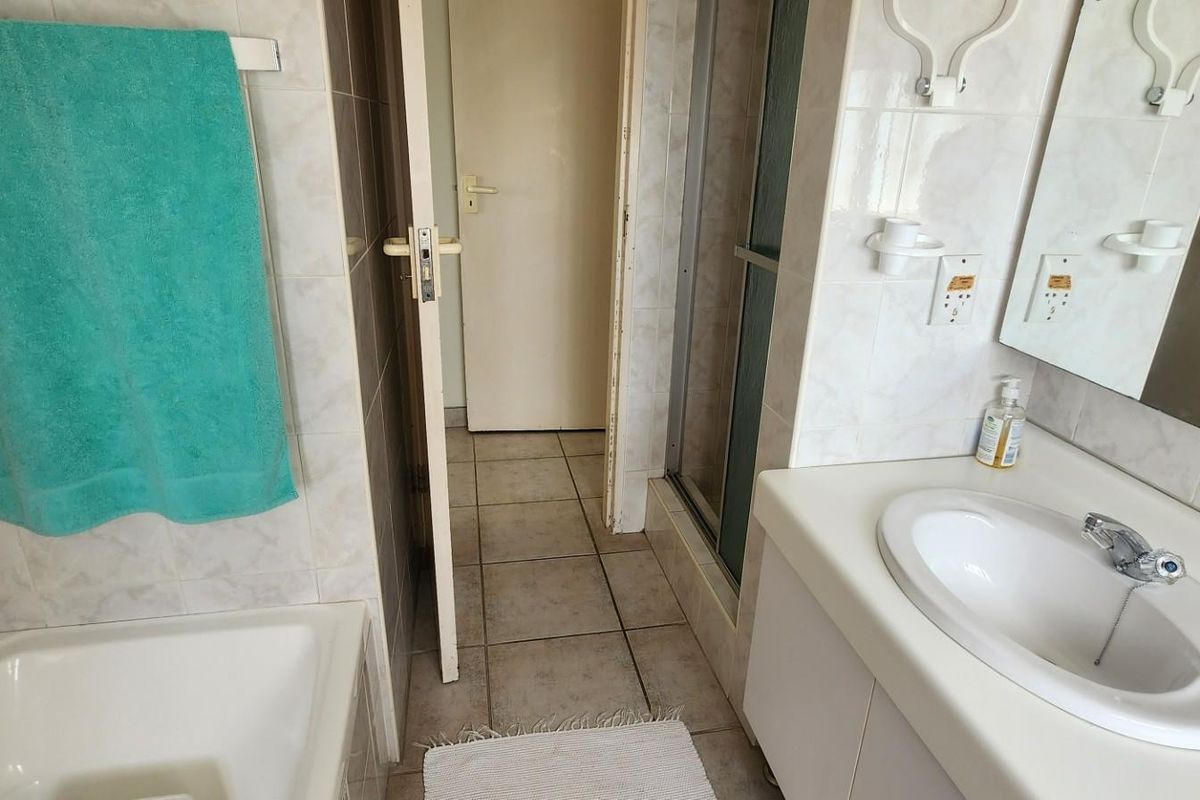 A functional bathroom featuring a built-in vanity with integrated basin, a separate shower enclosure, and a bathtub with tiled surround.