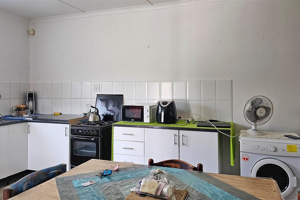 Functional kitchen area featuring white cabinetry, tiled splashback, and integrated stove, providing a practical workspace for daily meal preparation.