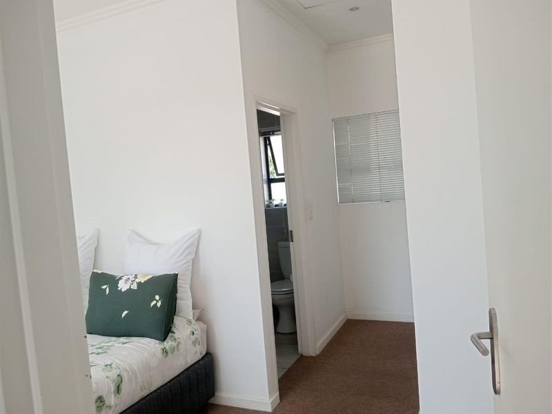 A bedroom featuring carpeted flooring and recessed lighting, with an adjoining en-suite bathroom visible through the doorway.