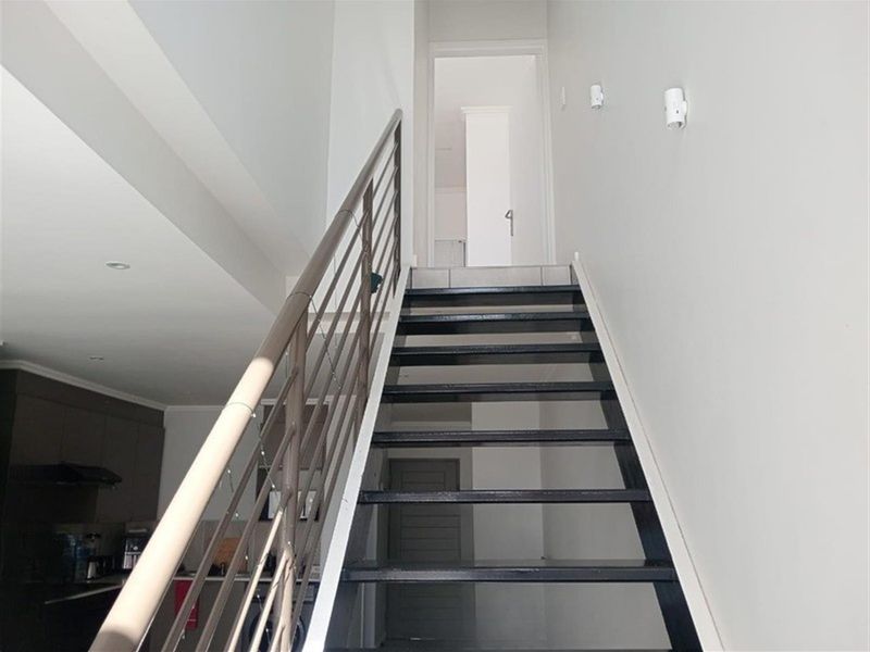 A modern staircase featuring a metal balustrade, connecting the lower living area to the upper level of the apartment.