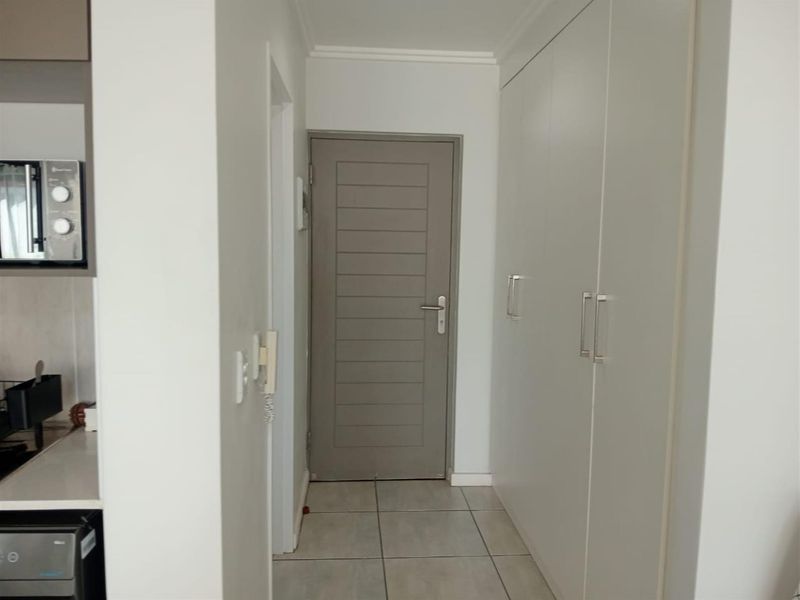 A clean, well-maintained hallway featuring neutral tiled flooring, built-in storage cupboards, and a modern internal door.