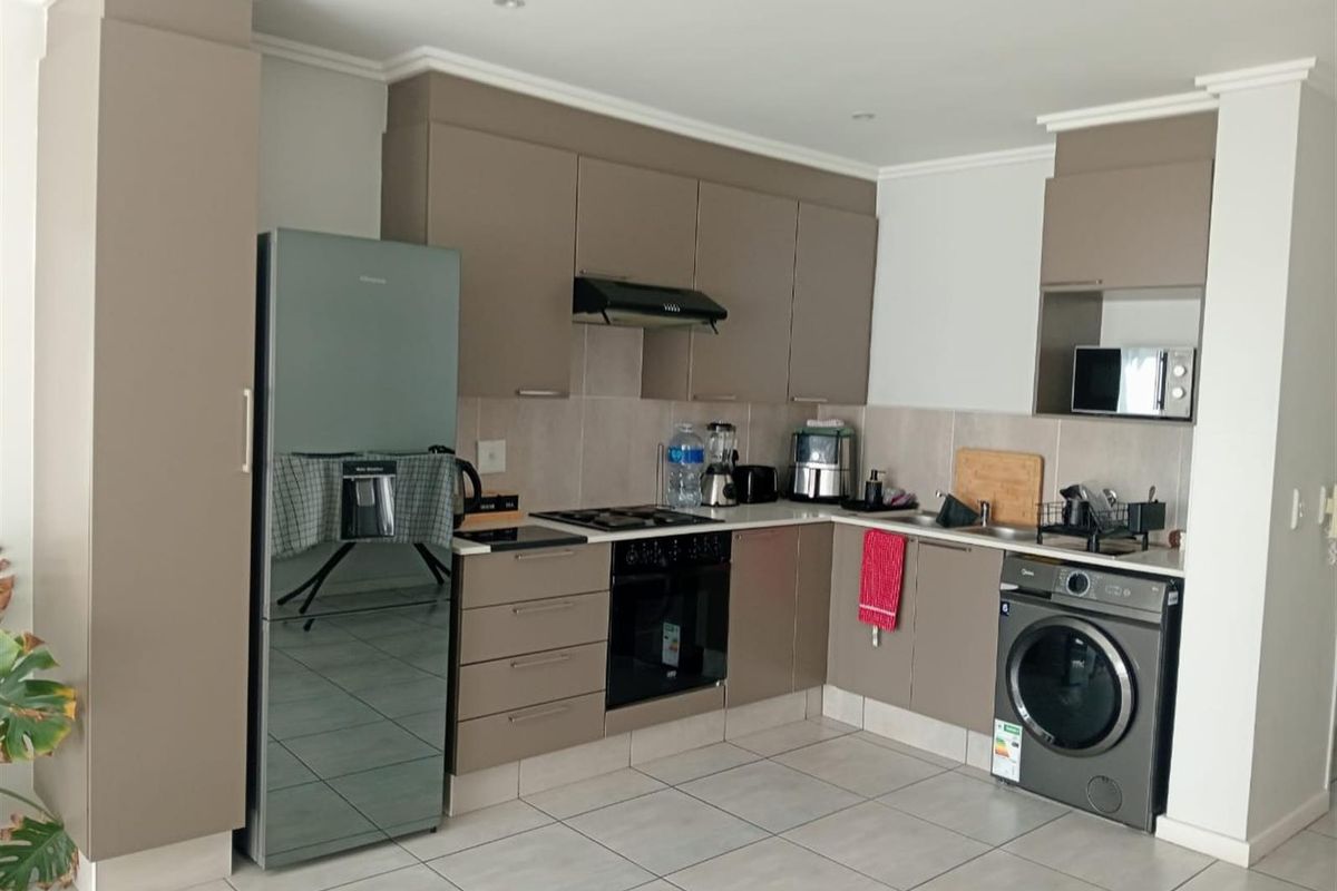 Modern kitchen featuring sleek taupe cabinetry, tiled flooring, integrated appliances, and a functional layout with a tiled backsplash and recessed lighting.