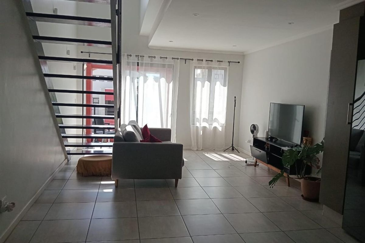 Spacious open-plan living area featuring modern tiled flooring, an architectural open-tread staircase, and large sliding doors providing ample natural light.
