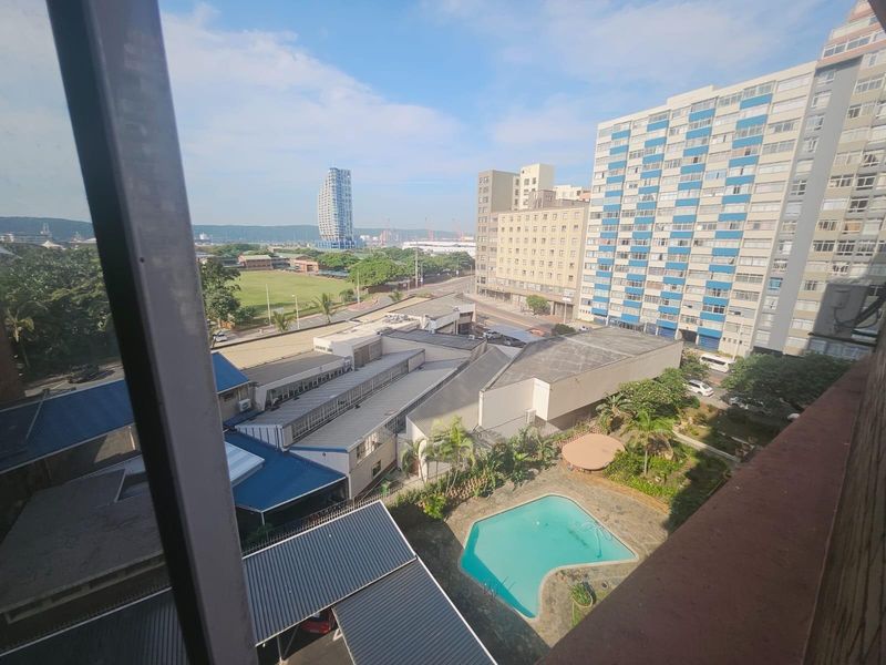 Elevated urban view overlooking a swimming pool, surrounding apartment buildings, and local infrastructure.