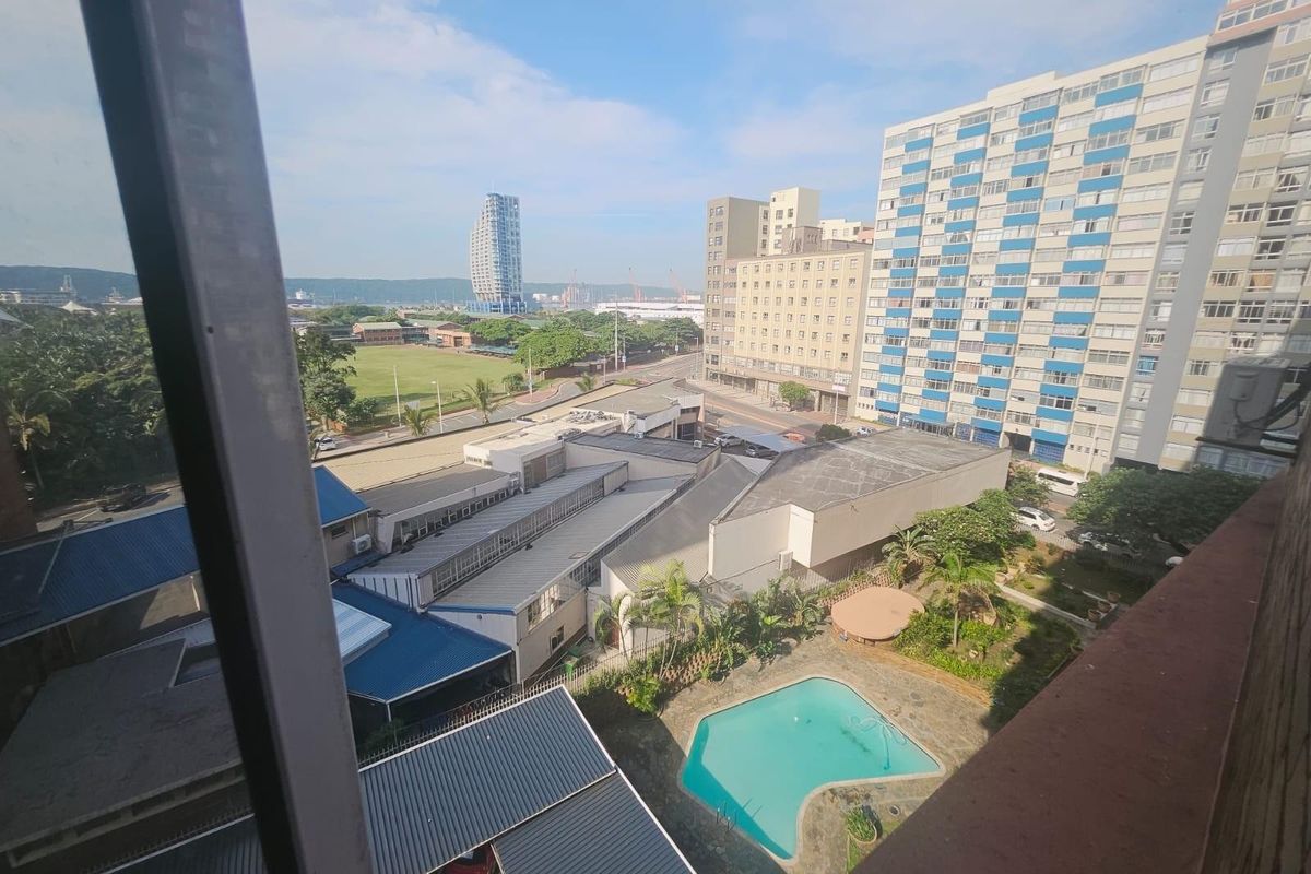 Elevated urban view overlooking a swimming pool, surrounding apartment buildings, and local infrastructure.