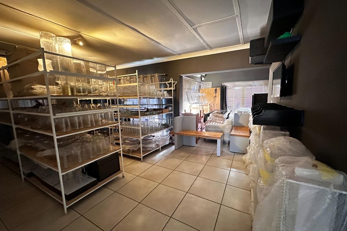 A spacious living area featuring tiled flooring and built-in shelving, currently utilized for storage with potential for versatile residential use.