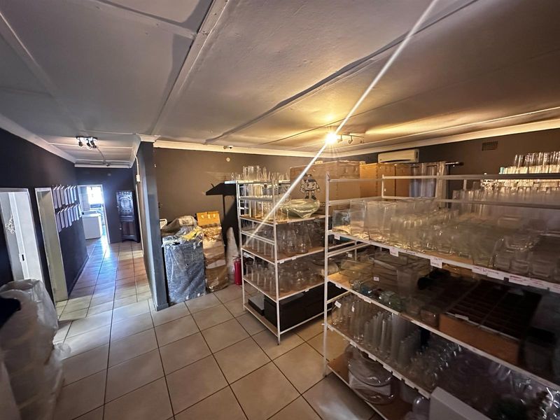 A utility or storage space featuring tiled flooring and a wall-mounted air conditioning unit, currently utilized for inventory storage.