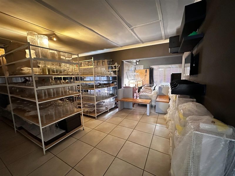 A spacious living area featuring tiled flooring and built-in shelving, currently utilized for storage with potential for versatile residential use.