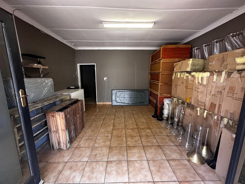 A functional garage space featuring tiled flooring and overhead lighting, currently utilized for storage.