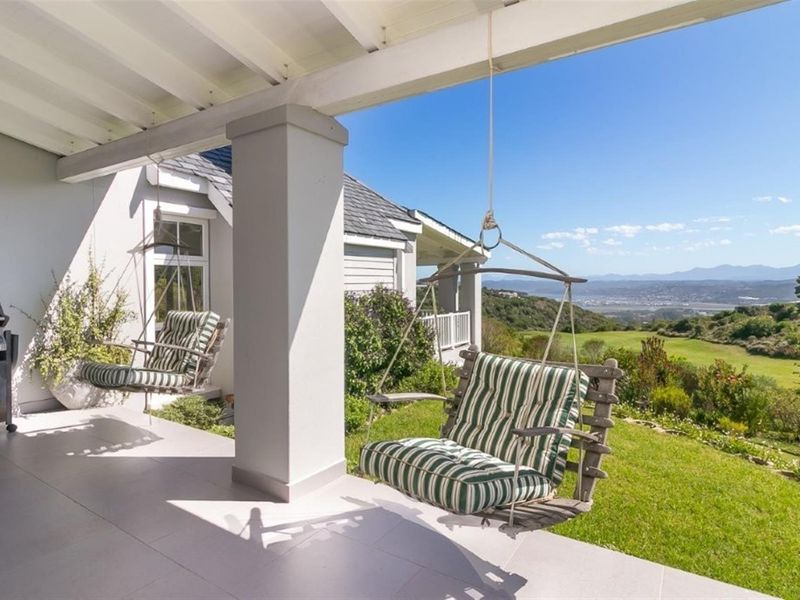 A covered patio featuring tiled flooring and exposed beam ceilings, offering scenic views of the surrounding landscape and garden.