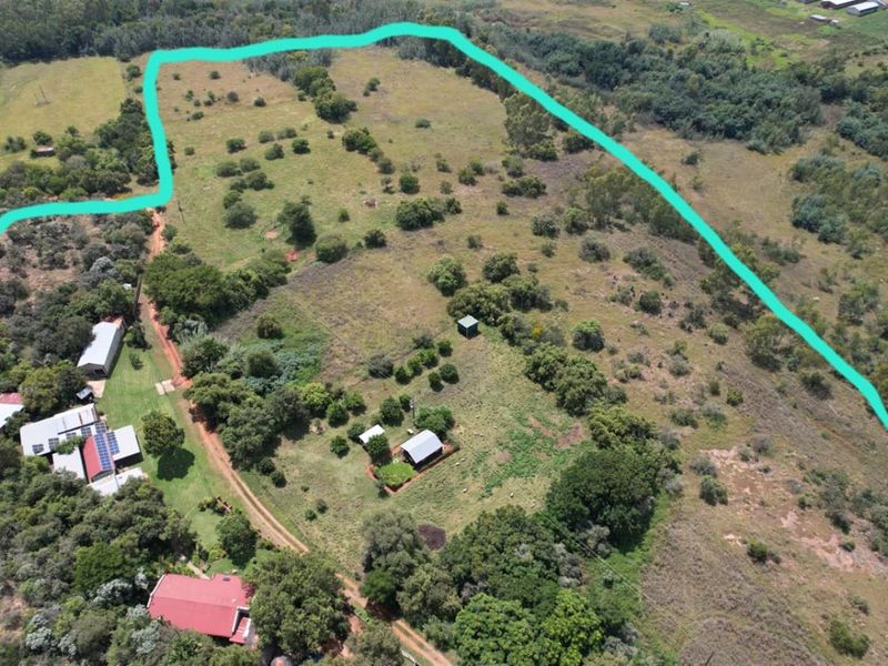 Aerial view of a rural farm property featuring multiple outbuildings, solar installations, and expansive open land with marked boundary lines.