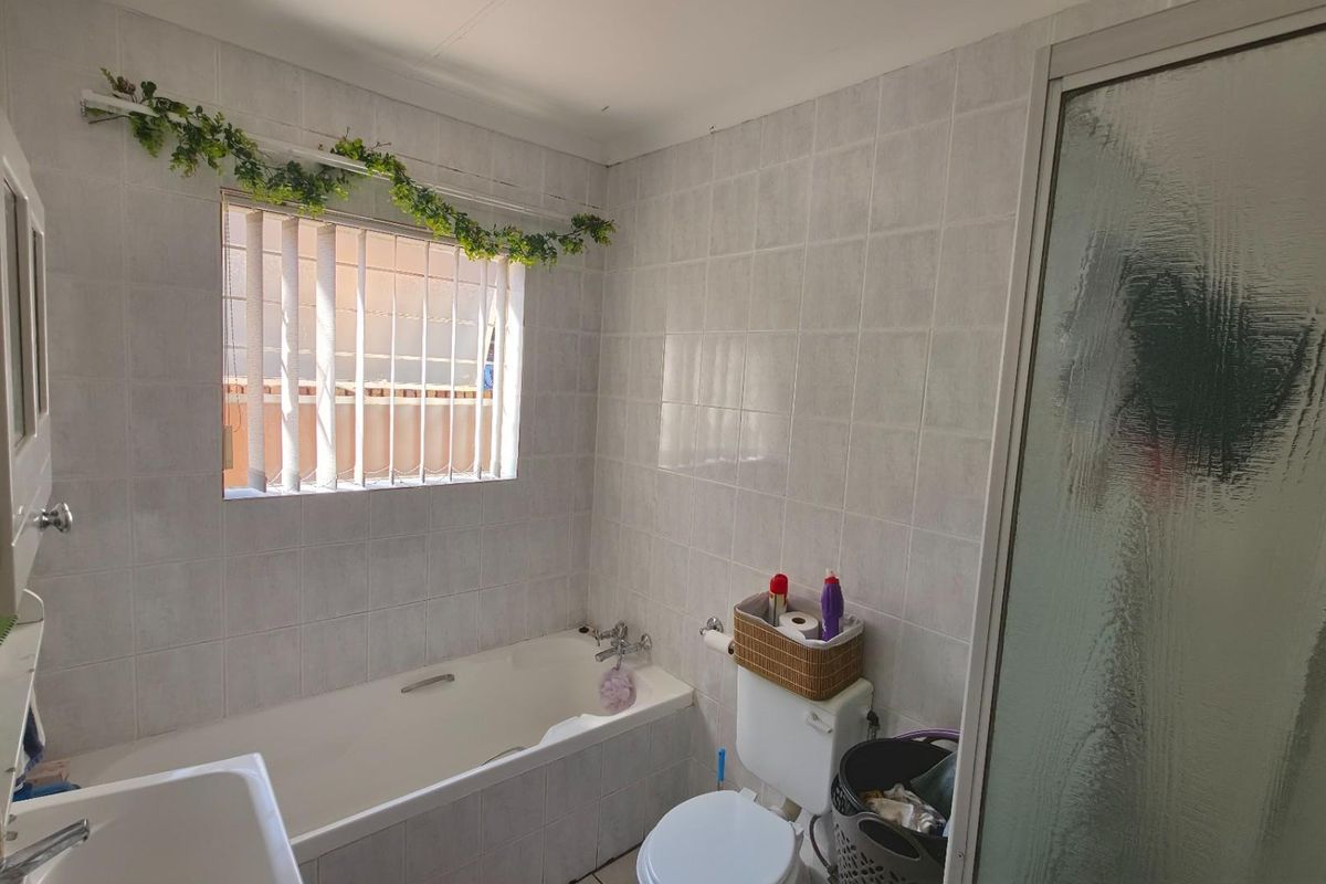 A functional bathroom featuring a built-in bathtub, a separate shower enclosure with a textured glass door, and a standard toilet.