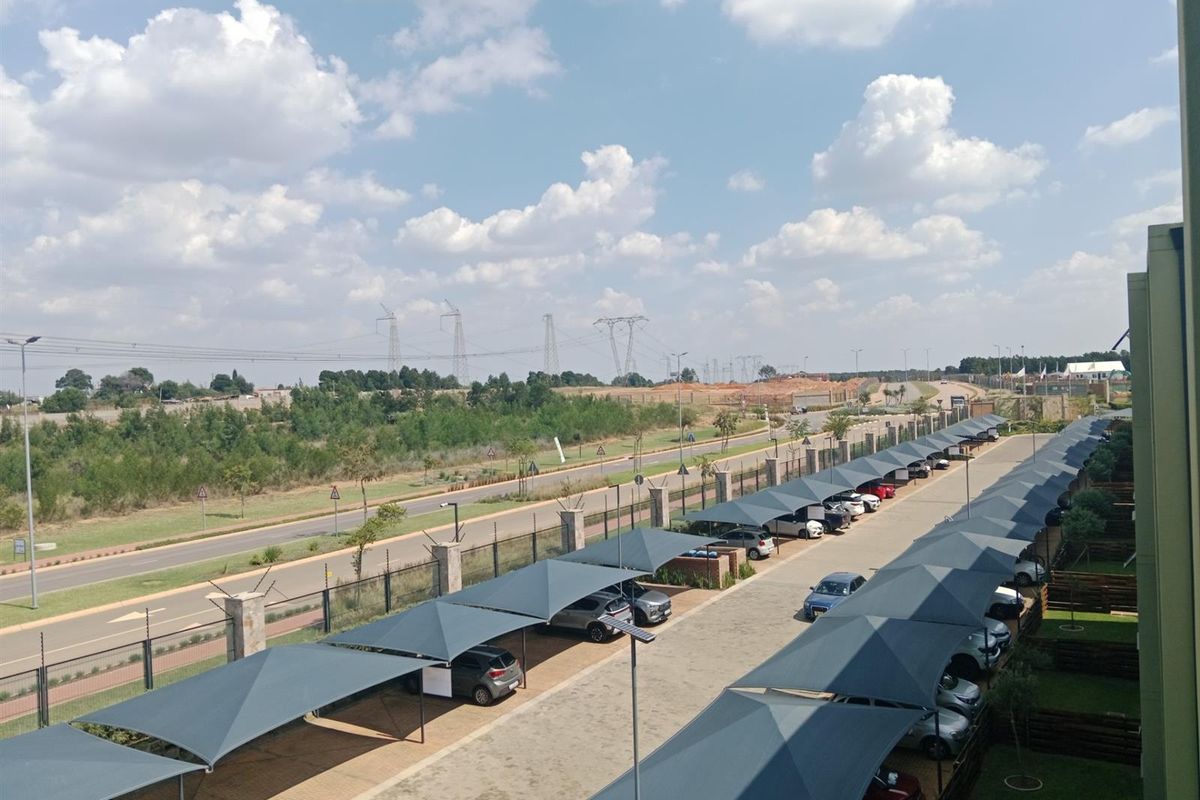 Elevated view of the apartment complex parking area featuring rows of shade cloth carports and paved driveway access.