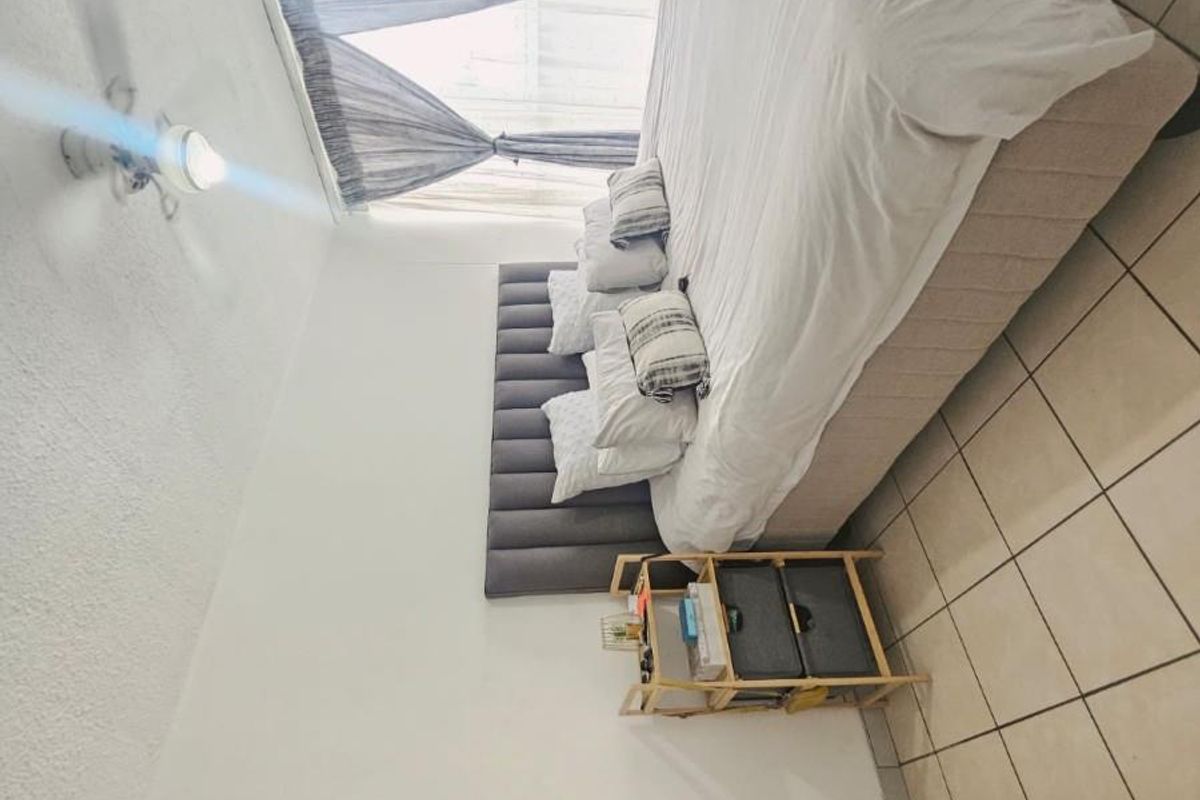 A bedroom featuring tiled flooring, a ceiling fan, and a built-in cupboard with minor wear on the door edge.