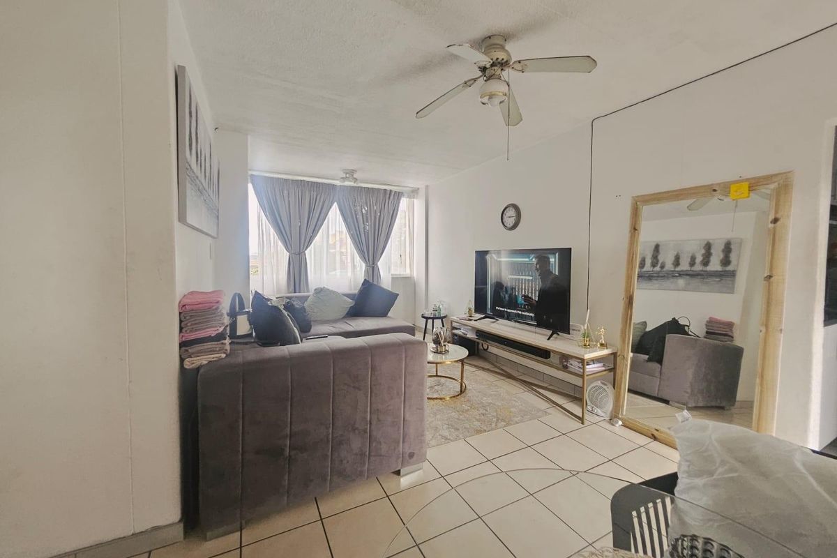 A living room featuring tiled flooring and a ceiling fan, providing a functional and comfortable space for relaxation.