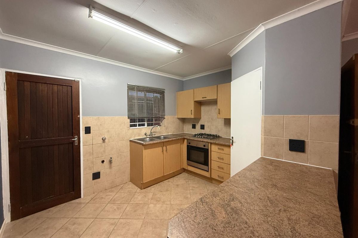 A functional kitchen featuring built-in cabinetry, laminate countertops, a gas hob, and an integrated oven, finished with tiled flooring and a neutral backsplash.