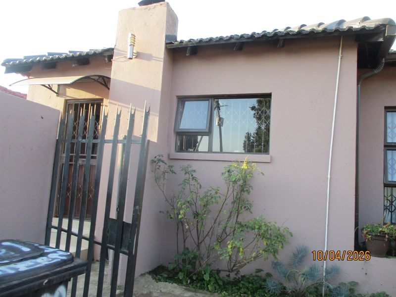 Exterior view of the property featuring a chimney, security gate, and window with burglar bars.